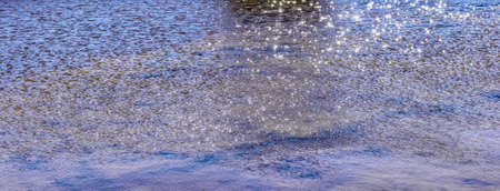 rippling of pond water waves with sun bunnies in sunlight and windの写真素材