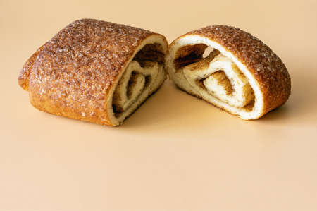 sweet cinnamon bun cut in two on orange background close up
