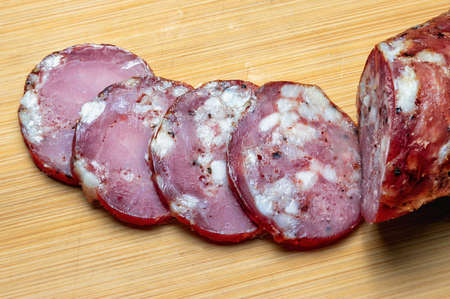 hot smoked ham pork sausage slices on a bamboo cutting board close-upの写真素材