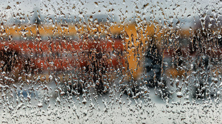 Raindrops of various shapes frozen into ice on the window glass in winter close as an abstract...