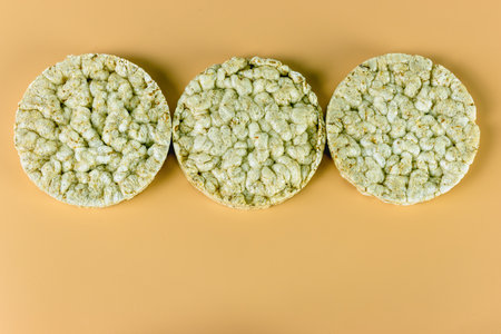 Three round wheat crackers on orange background close up top view