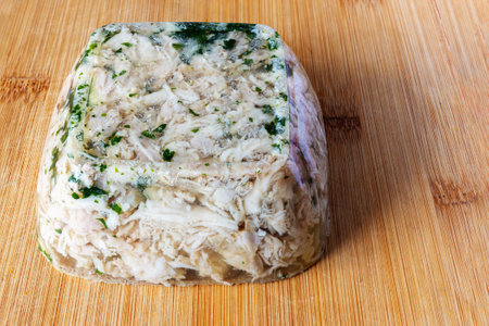 A piece of jelly jelly with chicken and parsley on a cutting board, close-up