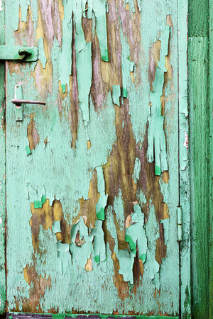 Peeling green paint on a wooden door with crack and peeling patternsの写真素材