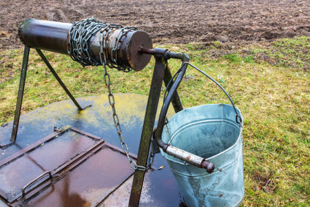 Old outdoor well with metal cover and roller, bucket for collecting water in the village in springの写真素材