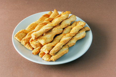 A stack of buttery yeast dough rolls on a plate on a brown background