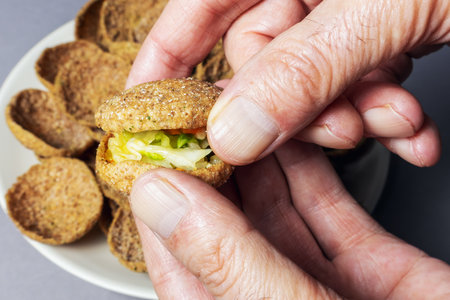 One bite of rye bread with garlic toast and vegetable filling in hands on blurred backgroundの写真素材
