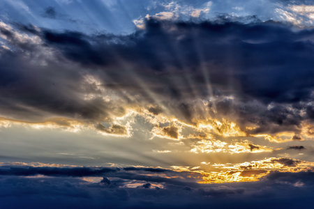 Colorful fiery evening sky at sunset with sun rays between clouds in spring