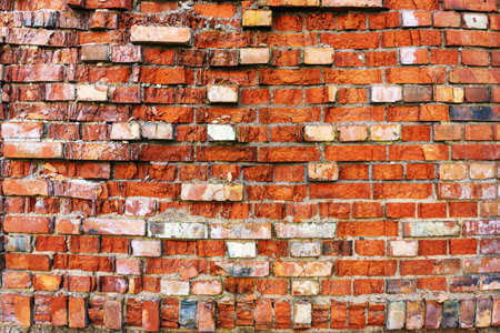Outdoors, an old crumbling red brick wall on a sunny day as a background