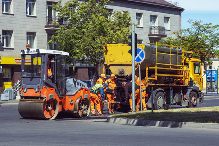 Road workers repair the asphalt on the street with shovels and technical equipment. Panevezys....