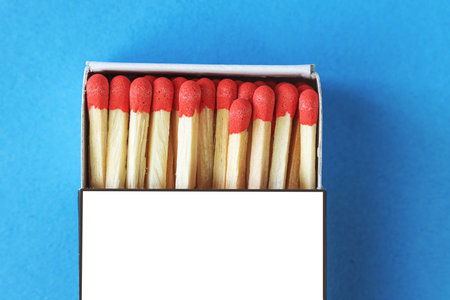 Paper matchbox with red match heads on blue background close up, place for textの写真素材