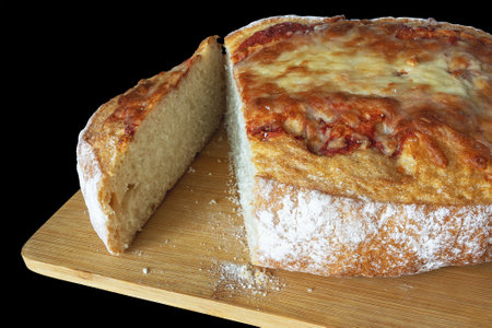 Italian bread with mozzarella cheese and tomato sauce on a bamboo cutting board on a black...