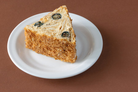 Shortcrust pastry roll with whipped cream and fresh blueberries served on a white plate on a brown...