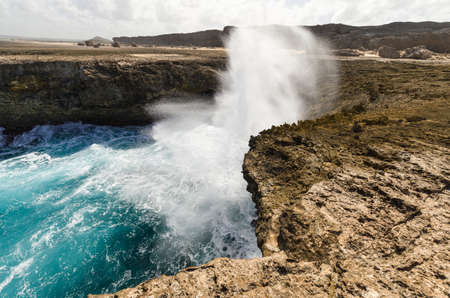 Surf and spray at caribbean coast, Bonaire. Blue an turquoise water at rocks.の写真素材