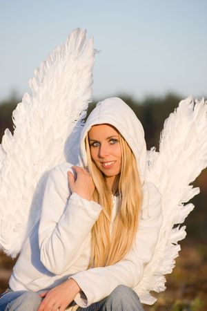 blonde girl with long hair and angel's wings on back and white hoodの写真素材