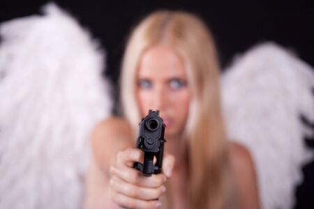 Angel with white wings, aiming weapon in his arm.  Black background.の写真素材
