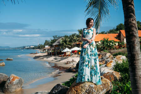 Happy girl standing on rocks surrounded by tropical palmsの写真素材