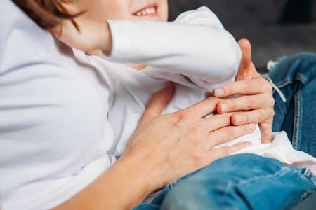 Unrecognizable mother holding son in her arms close up hands