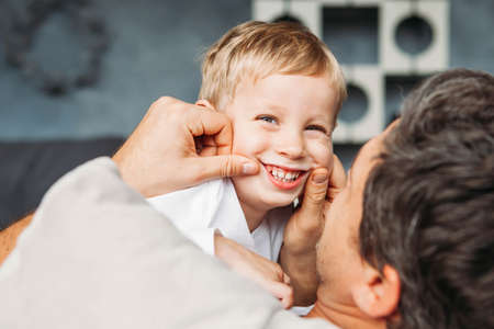 Father lying on the sofa and playing with his little sonの写真素材