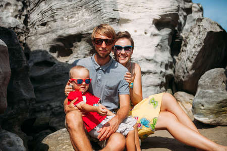 Family laughing siting on the rocks tropical beachの写真素材