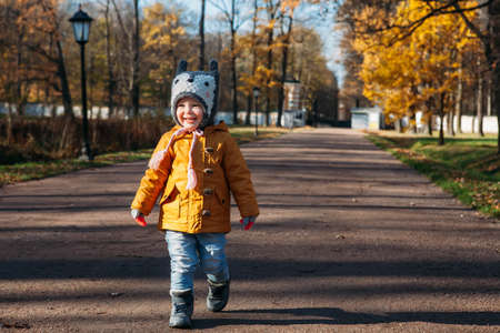 Baby girl walking smiling in the autumn park