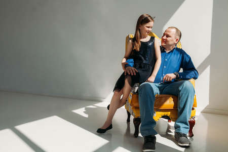 photo of Father with his little daughter sit in armchair on white backgroundの写真素材