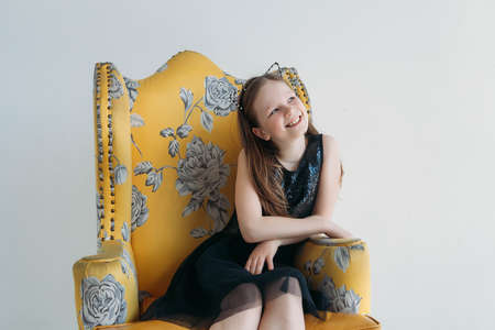 Cute Little girl smiling in black dress siting on the chairの写真素材