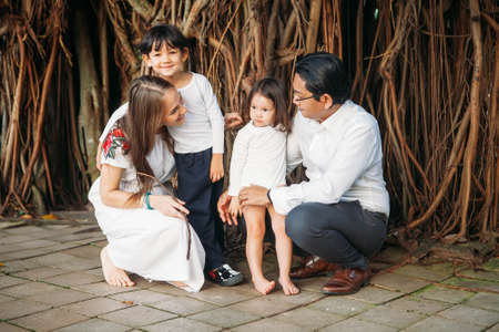 happy stylish parents holding hands with son and daughter walking in jungles park, amazing family moment. fathers mothers dayの写真素材