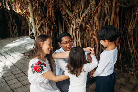 happy stylish parents holding hands with son and daughter walking in jungles park, amazing family moment. fathers mothers dayの写真素材