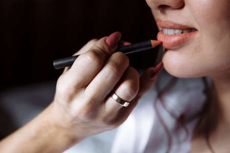 Close-up of a girl's face and makeup artist's brush. The girl is doing evening makeup.の写真素材