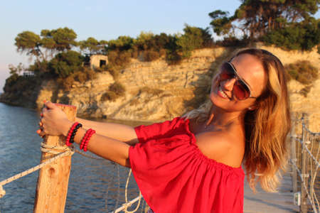 beautiful girl in a red dress, laughs beautifully against a background of high mountains and a blue skyの写真素材