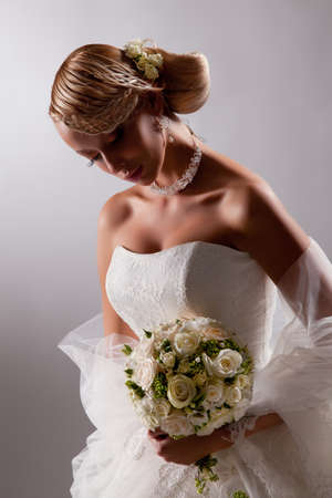 Young beautiful blonde woman in a wedding dress on a studio backgroundの写真素材