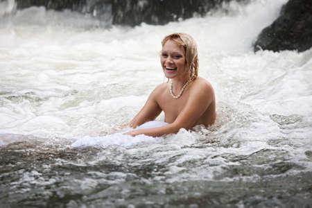 Young naked woman swimming in a riverの写真素材