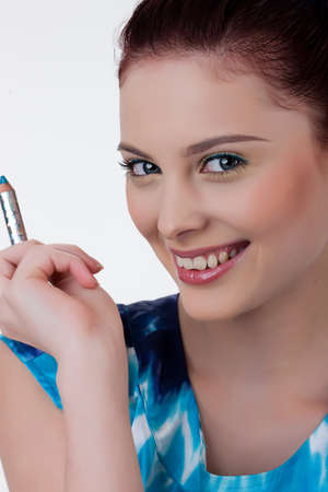 Young beautiful woman applying cosmetics onto her faceの写真素材