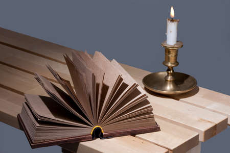 Old book and candle in an old candlestickの写真素材