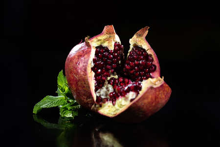 Close up pomegranade and mint on reflecting balck glass