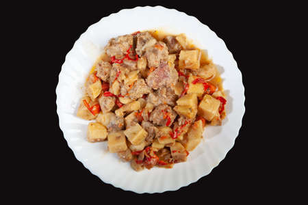 Plate with roasted meat and potatoes on a black studio background