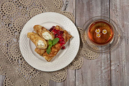 Plate with pancakes and a cup of tea on a wooden deskの写真素材