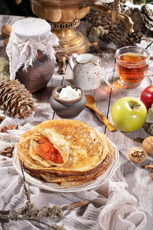 Pancakes, tea, cream and fruits on a fabric background
