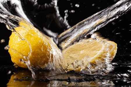 Lemon and pouring water on a black glass backgroundの写真素材