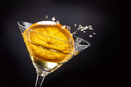 Slice of orange falling into the glass of juiceの写真素材