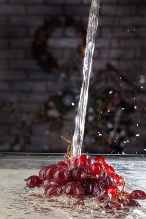 Bunch of grapes and stream of water on a studio backgroundの写真素材