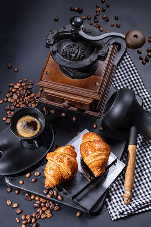 Cup of coffee, mill, beans and pastry on a black backgroundの写真素材