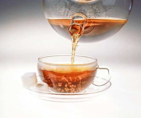 Cup of tea and pouring tea on a stduio backgroundの写真素材
