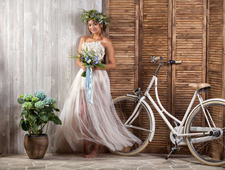 Young beautiful girl in a wedding dress with a bicycleの写真素材