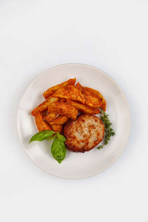 Cutlet, potatoes and greenery on a plate on isolated studio backgroundの写真素材