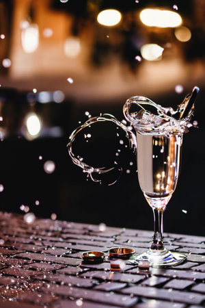 Golden rings falling into glass with wineの素材