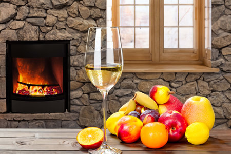 Different fruits and glass of wine on a table near the fireplaceの素材