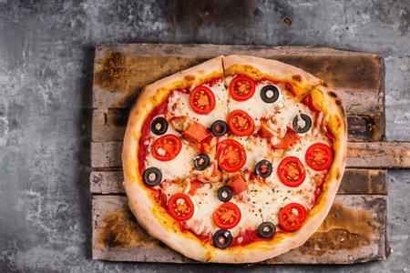 Pizza with ham on an old wooden boardの素材