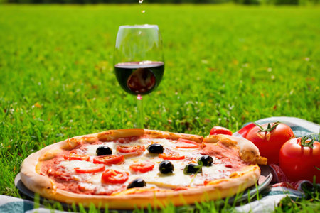 Pizza with ham, cheese and tomatoes on the green grass lawnの素材