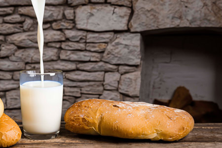 Glass of milk and pieces of bread near the fireplaceの素材